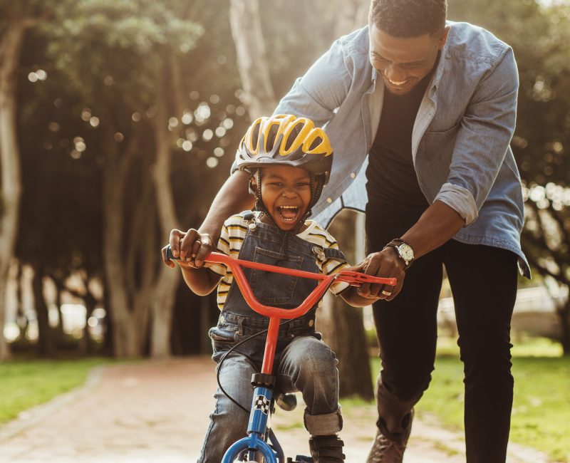 A father helping his son ride a bike.