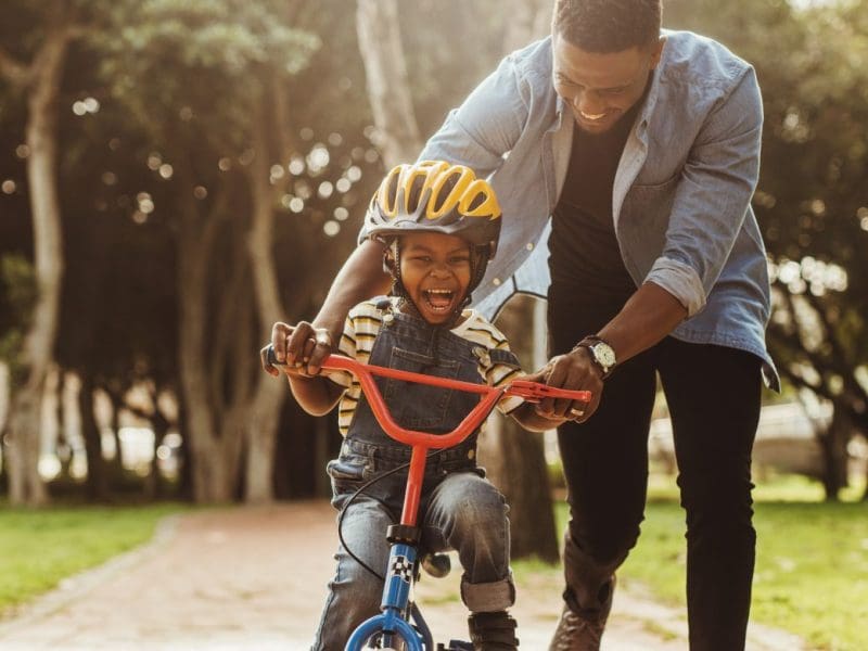 A father helping his son ride a bike.